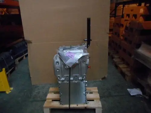 Remeha Wärmetauscher in einem Lager auf einer Holzpalette, teilweise eingepackt. Hintergrund zeigt weitere Kartons und Regale.